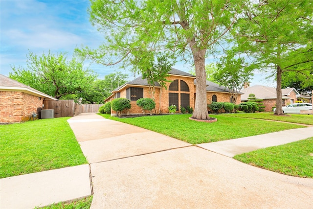 view of front facade with a front lawn, fence, cooling unit, brick siding, and concrete driveway