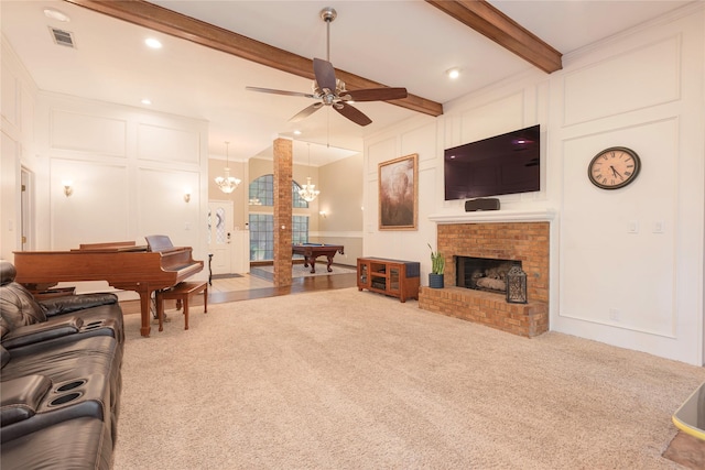carpeted living area featuring beam ceiling, a decorative wall, a brick fireplace, ceiling fan with notable chandelier, and visible vents