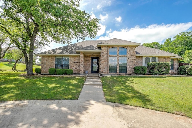 view of front of house featuring brick siding, a shingled roof, and a front lawn