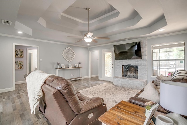 living area with baseboards, visible vents, wood finished floors, and a raised ceiling