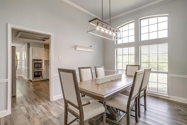 dining room featuring crown molding, baseboards, an inviting chandelier, and light wood-style floors
