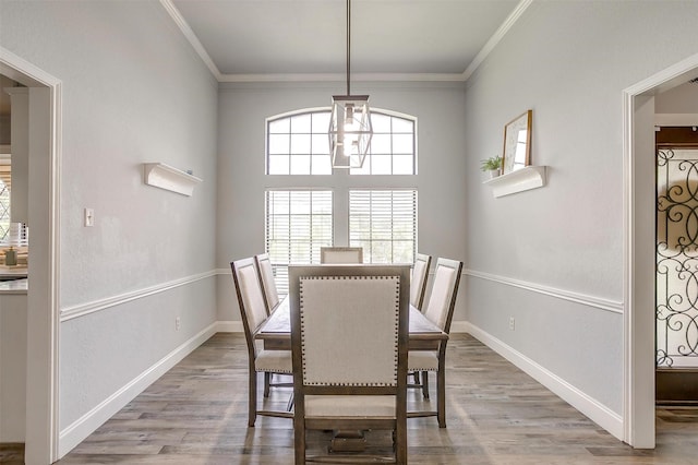 dining space featuring crown molding, baseboards, and wood finished floors