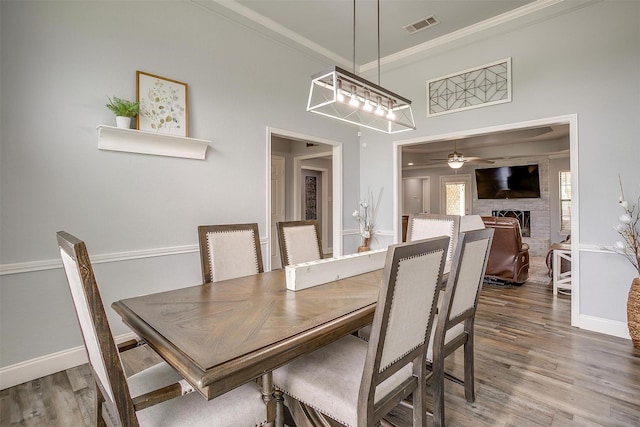 dining area with crown molding, a ceiling fan, baseboards, and wood finished floors