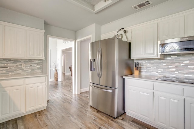 kitchen with light countertops, tasteful backsplash, stainless steel appliances, and visible vents