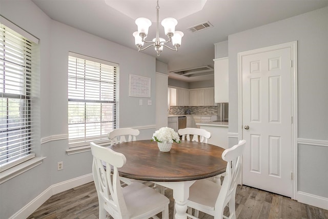 dining space featuring light wood-style floors, baseboards, a notable chandelier, and visible vents
