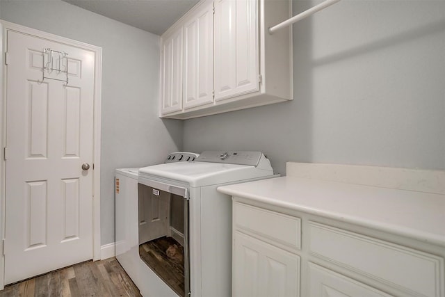 laundry room with light wood-style floors, washer and clothes dryer, and cabinet space