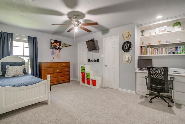 carpeted bedroom featuring baseboards, built in desk, and ceiling fan
