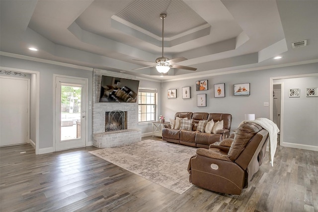 living area featuring visible vents, a ceiling fan, a tray ceiling, and a healthy amount of sunlight