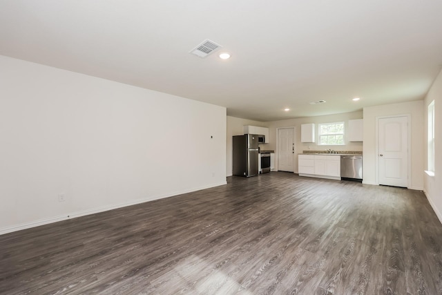 unfurnished living room featuring dark wood-style flooring, a sink, recessed lighting, baseboards, and visible vents