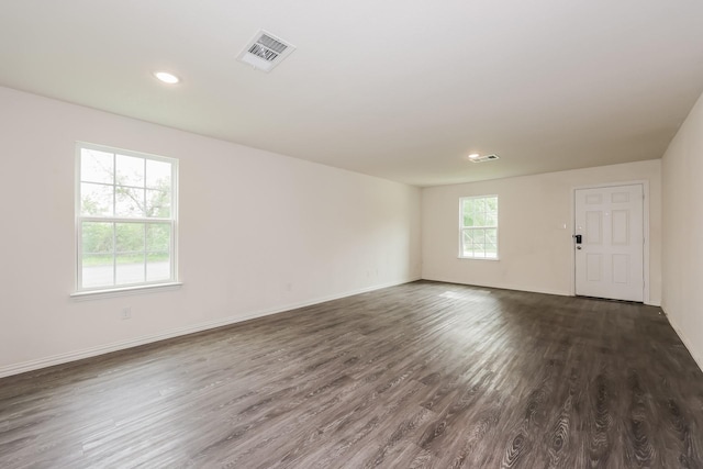 empty room featuring dark wood-style flooring, baseboards, visible vents, and recessed lighting