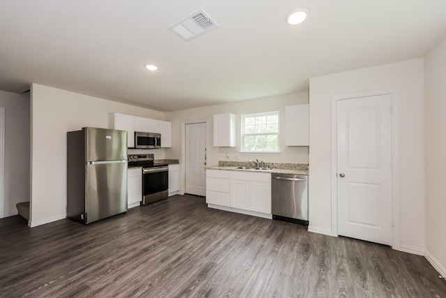 kitchen featuring visible vents, dark wood finished floors, a sink, white cabinets, and stainless steel appliances