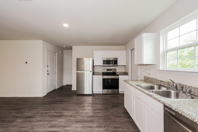 kitchen featuring dark wood-style flooring, appliances with stainless steel finishes, a sink, light countertops, and white cabinetry