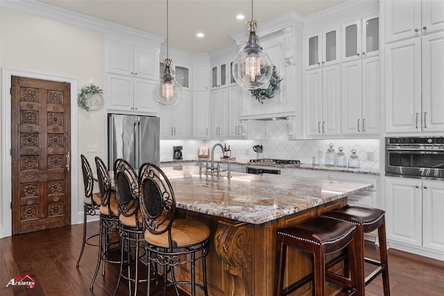kitchen with a sink, appliances with stainless steel finishes, dark wood-style flooring, and light stone counters