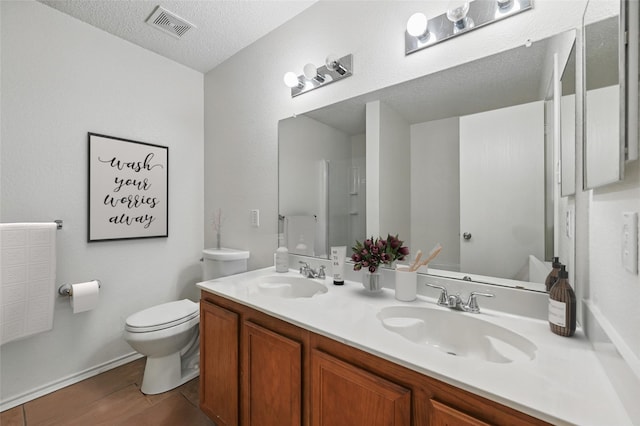 2011 Kalgary Ln, Grand Prairie, TX 75052 - bathroom with toilet, double vanity, and a textured ceiling