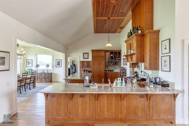 990 County Road 621, Tuscola, TX 79562 - kitchen with brown cabinets, a peninsula, light stone countertops, and premium range hood
