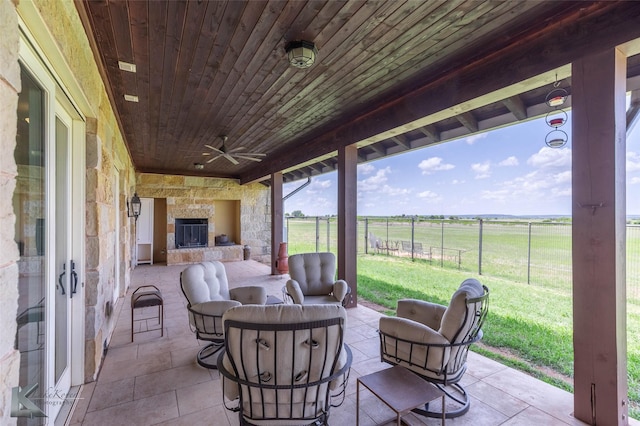 990 County Road 621, Tuscola, TX 79562 - view of patio with a ceiling fan, an outdoor living space with a fireplace, fence, and a rural view