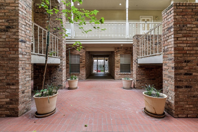doorway to property with brick siding, a balcony, and a patio area