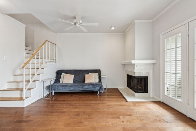 living area featuring ornamental molding, a wealth of natural light, wood finished floors, and stairway