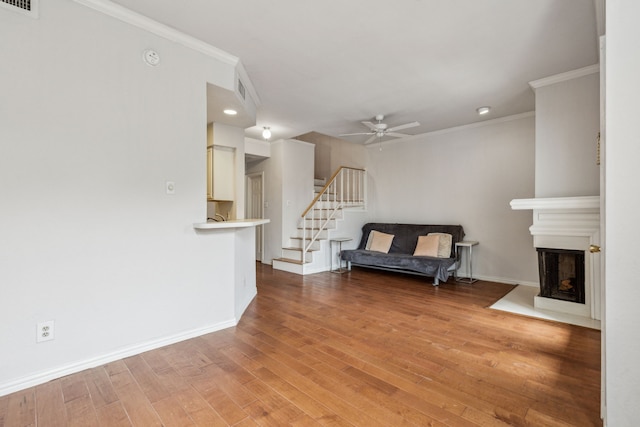 interior space with stairs, a ceiling fan, ornamental molding, and light wood-style flooring