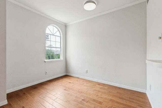 empty room featuring light wood-style floors, ornamental molding, and baseboards