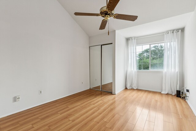 unfurnished bedroom with ceiling fan, baseboards, a closet, lofted ceiling, and light wood-style floors