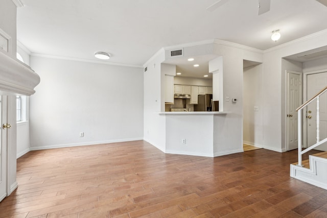 unfurnished living room featuring stairs, crown molding, visible vents, and light wood finished floors