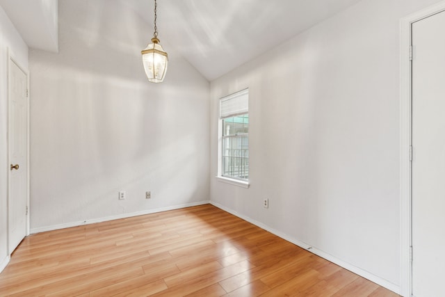 spare room featuring baseboards, wood finished floors, and lofted ceiling
