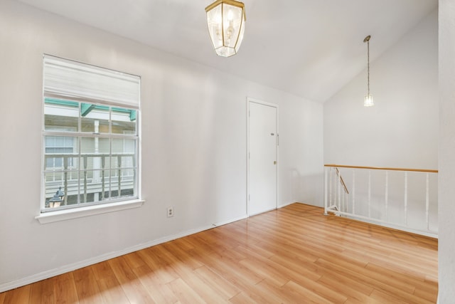 spare room with baseboards, vaulted ceiling, and wood finished floors