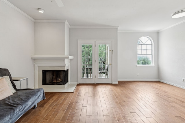 living area with ceiling fan, crown molding, a fireplace, wood finished floors, and baseboards