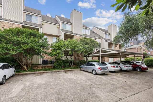 view of building exterior with a residential view and covered and uncovered parking