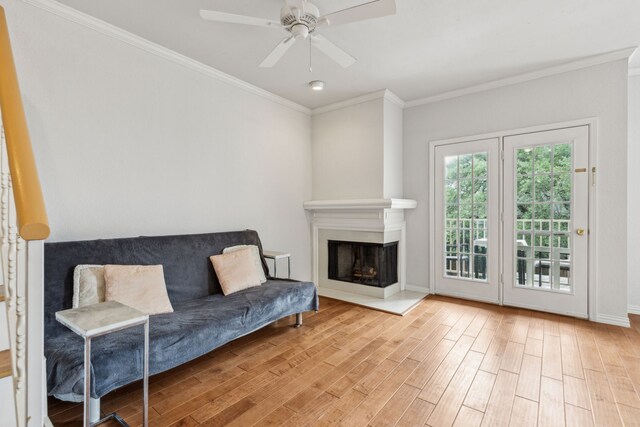 living room featuring baseboards, ceiling fan, ornamental molding, and wood finished floors
