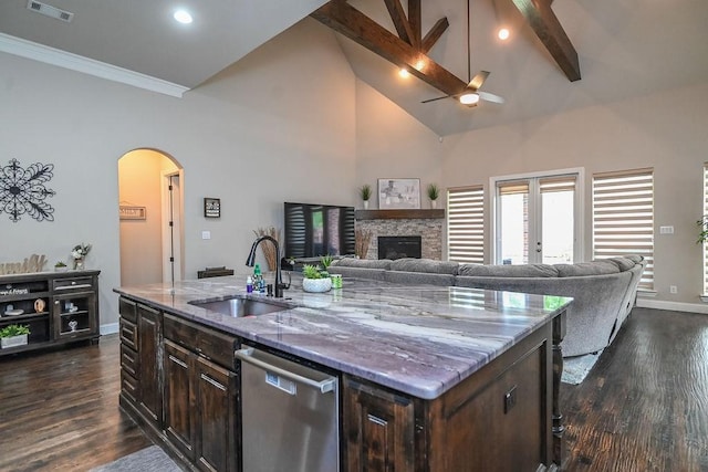 kitchen featuring visible vents, stainless steel dishwasher, high vaulted ceiling, arched walkways, and a sink