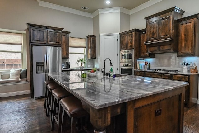 kitchen featuring crown molding, a sink, visible vents, stainless steel appliances, and a spacious island