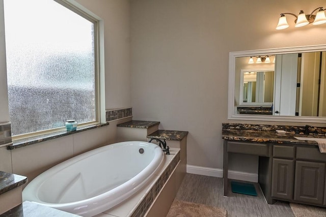 bathroom featuring vanity, baseboards, a bath, and wood finished floors