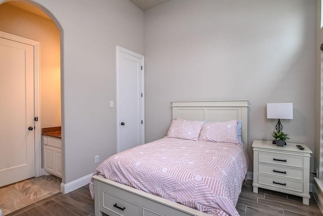 bedroom with baseboards, arched walkways, and wood tiled floor