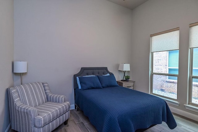 bedroom with baseboards, multiple windows, and wood finished floors