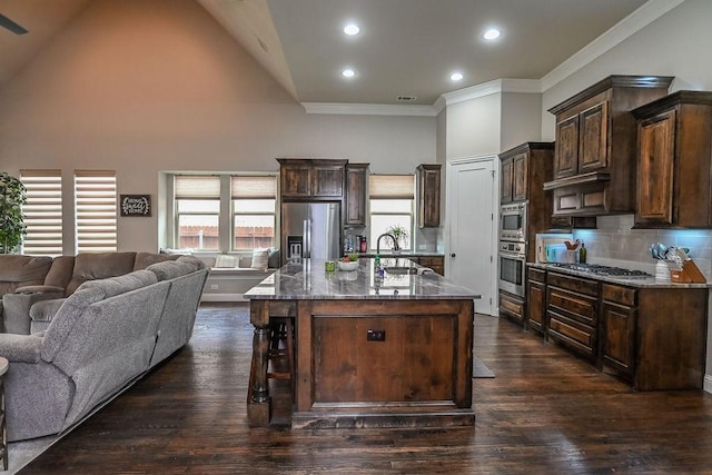kitchen with a sink, high vaulted ceiling, dark stone countertops, open floor plan, and stainless steel appliances