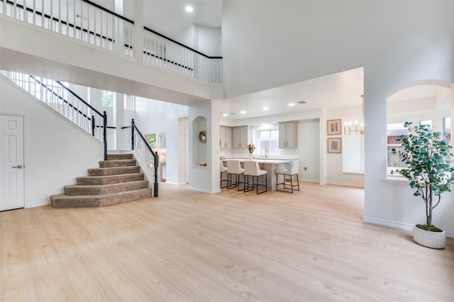 foyer entrance featuring a high ceiling, baseboards, and light wood-style floors