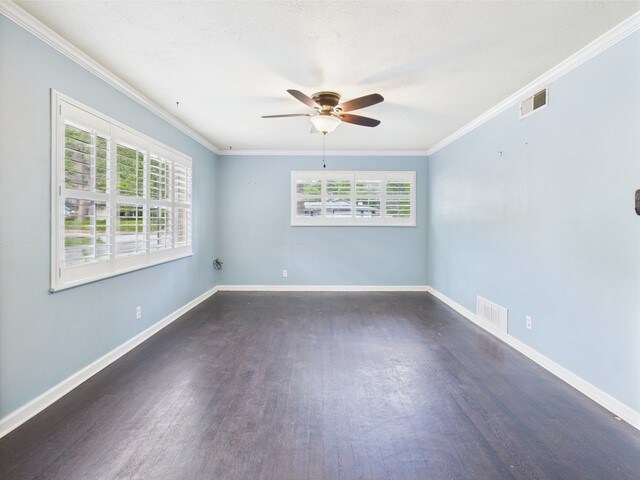 unfurnished room featuring ornamental molding, wood finished floors, and a wealth of natural light