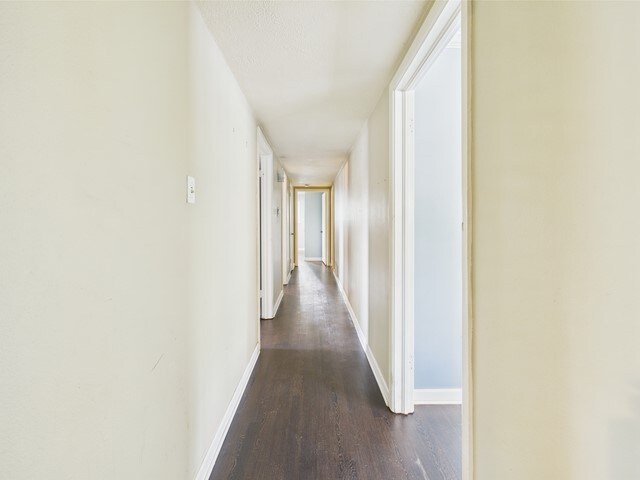hall with baseboards and dark wood-style floors