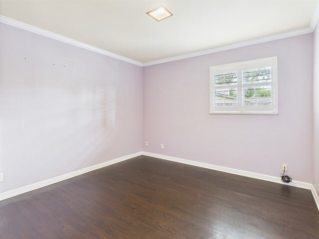 unfurnished room with baseboards, ornamental molding, and dark wood finished floors
