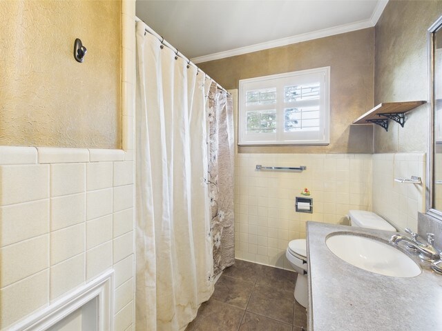 full bathroom featuring crown molding, toilet, tile patterned floors, and tile walls