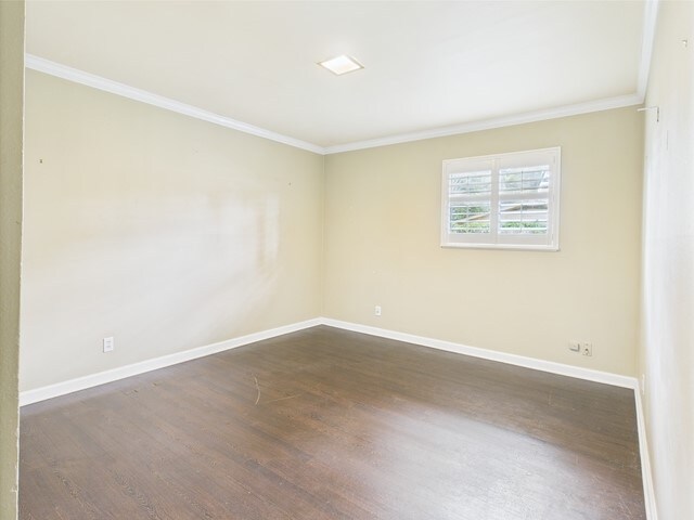 unfurnished room featuring baseboards, ornamental molding, and dark wood-type flooring
