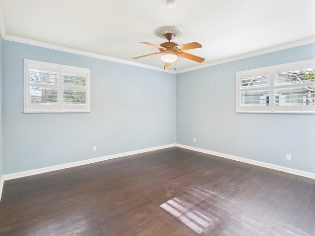 spare room featuring crown molding, dark wood-style flooring, and ceiling fan