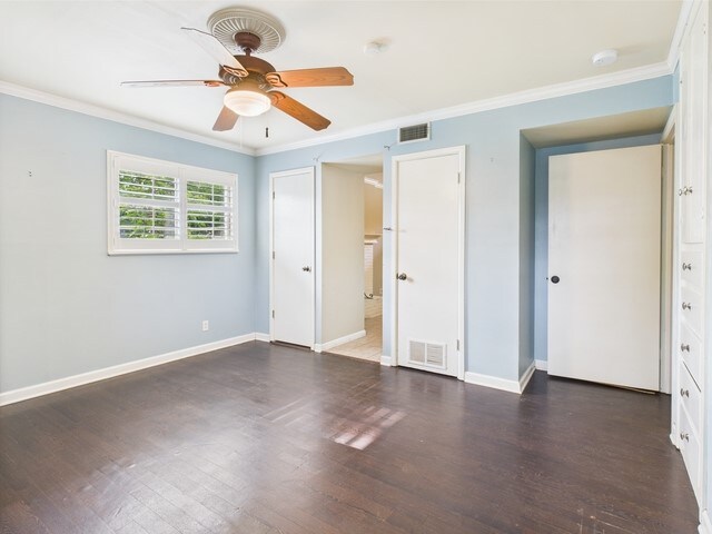 unfurnished bedroom featuring crown molding, baseboards, wood finished floors, and visible vents