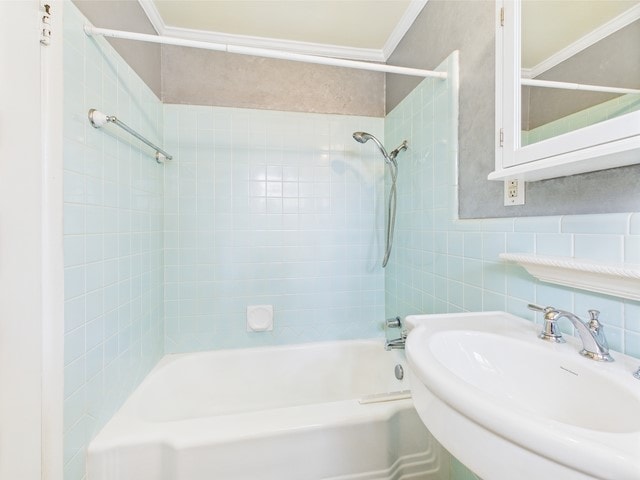 full bathroom with crown molding, a sink, shower / bathing tub combination, and tile walls
