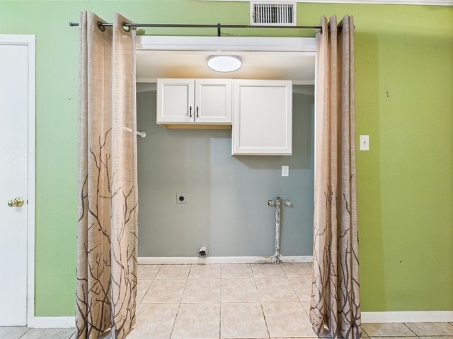 washroom with visible vents, light tile patterned flooring, baseboards, electric dryer hookup, and cabinet space