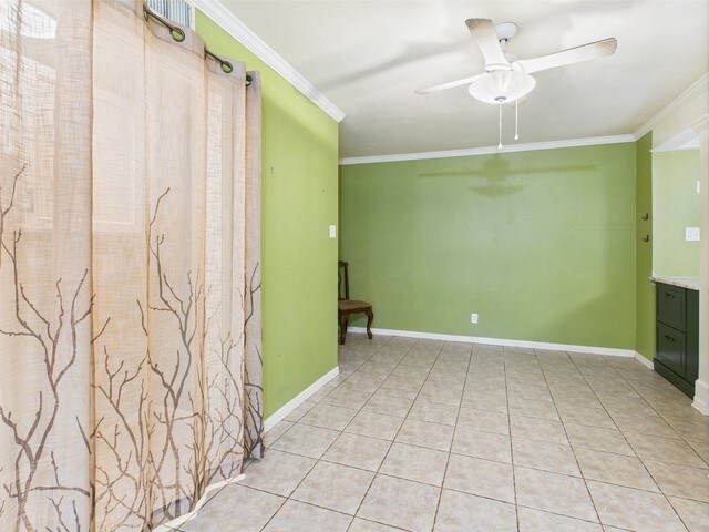 unfurnished room with crown molding, light tile patterned floors, ceiling fan, and baseboards
