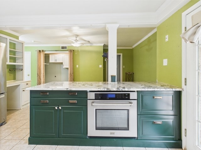 kitchen featuring decorative columns, appliances with stainless steel finishes, light tile patterned floors, green cabinets, and ornamental molding