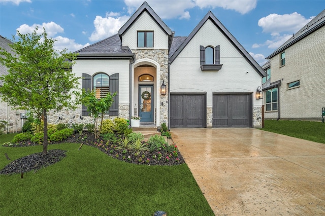 french country style house with brick siding, a front yard, and stone siding